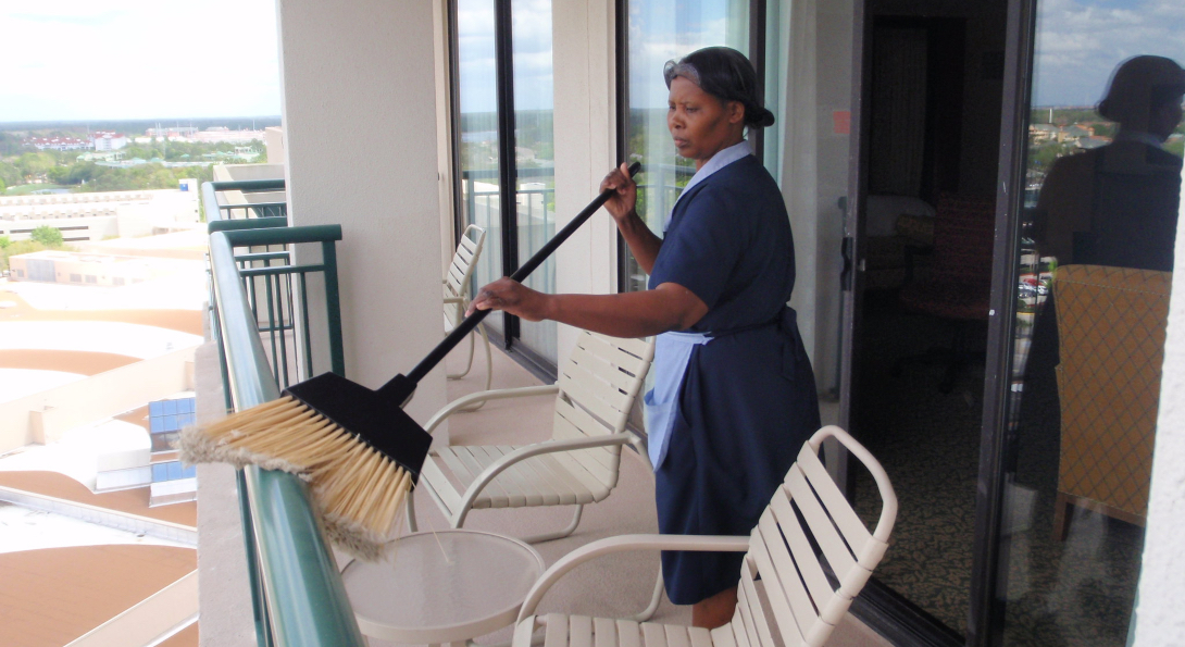 A housekeeper sweeps off the railing of a balcony at a Marriott hotel.