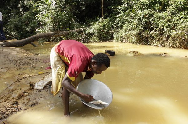 A small scale miner pans for gold in a small pond in Tanzania.